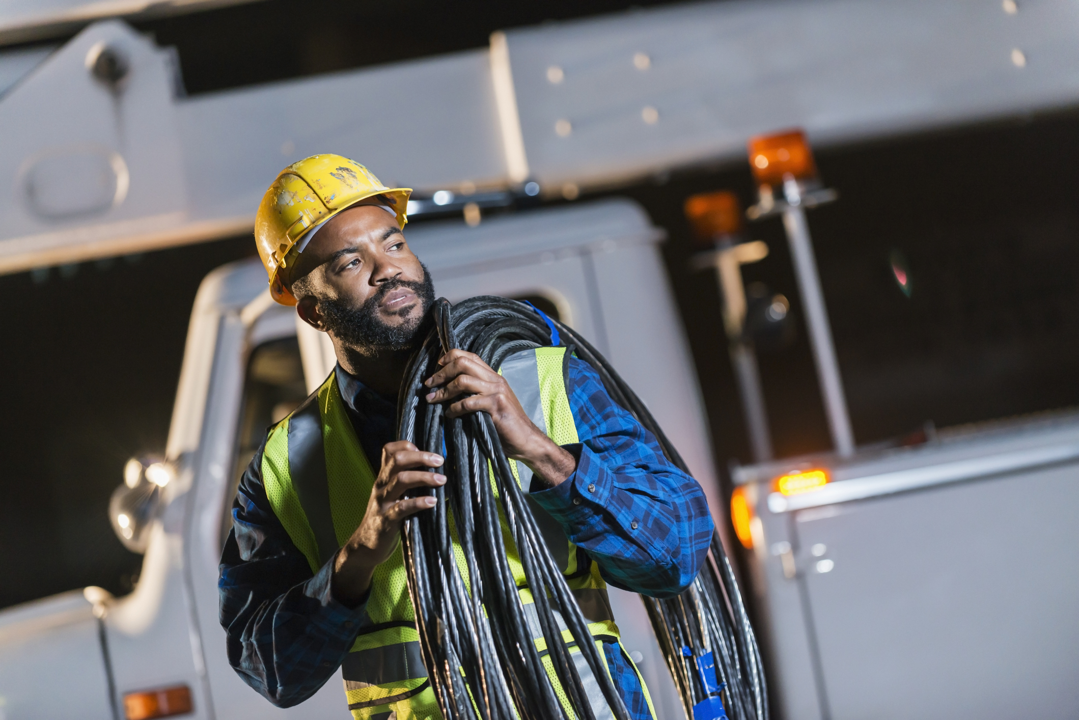 African American man with cherry picker truck industrial construction technician working in a backhoe tractor